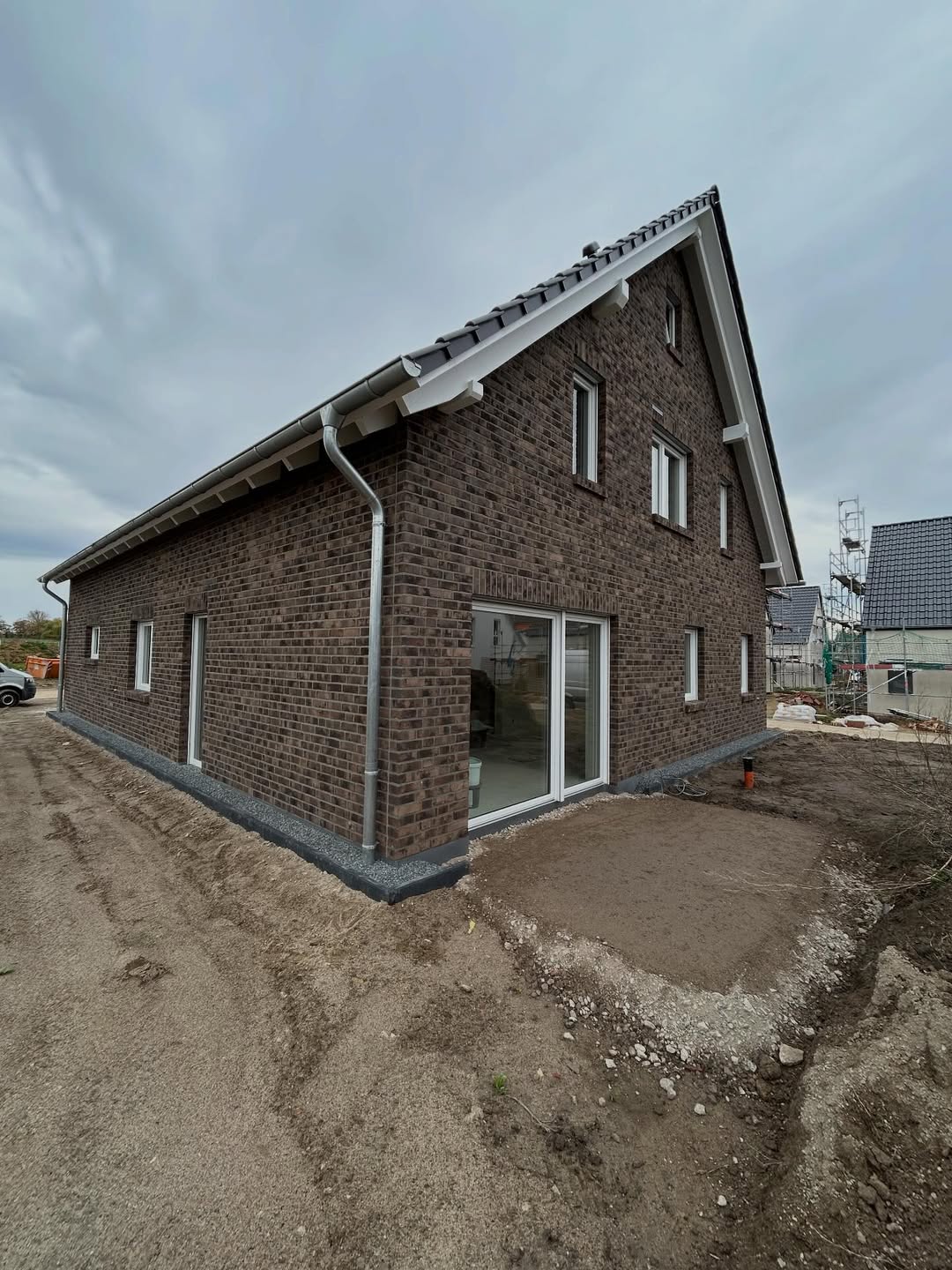 Giebelhaus in dunkelgrauem Klinker mit weißen Fenstern