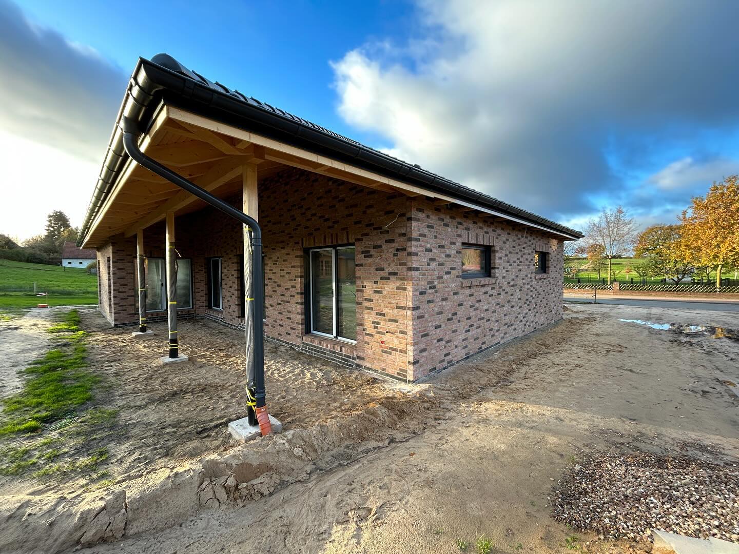 Bungalow mit Klinkerfassade und überdachtem Holzvordach auf der Baustelle