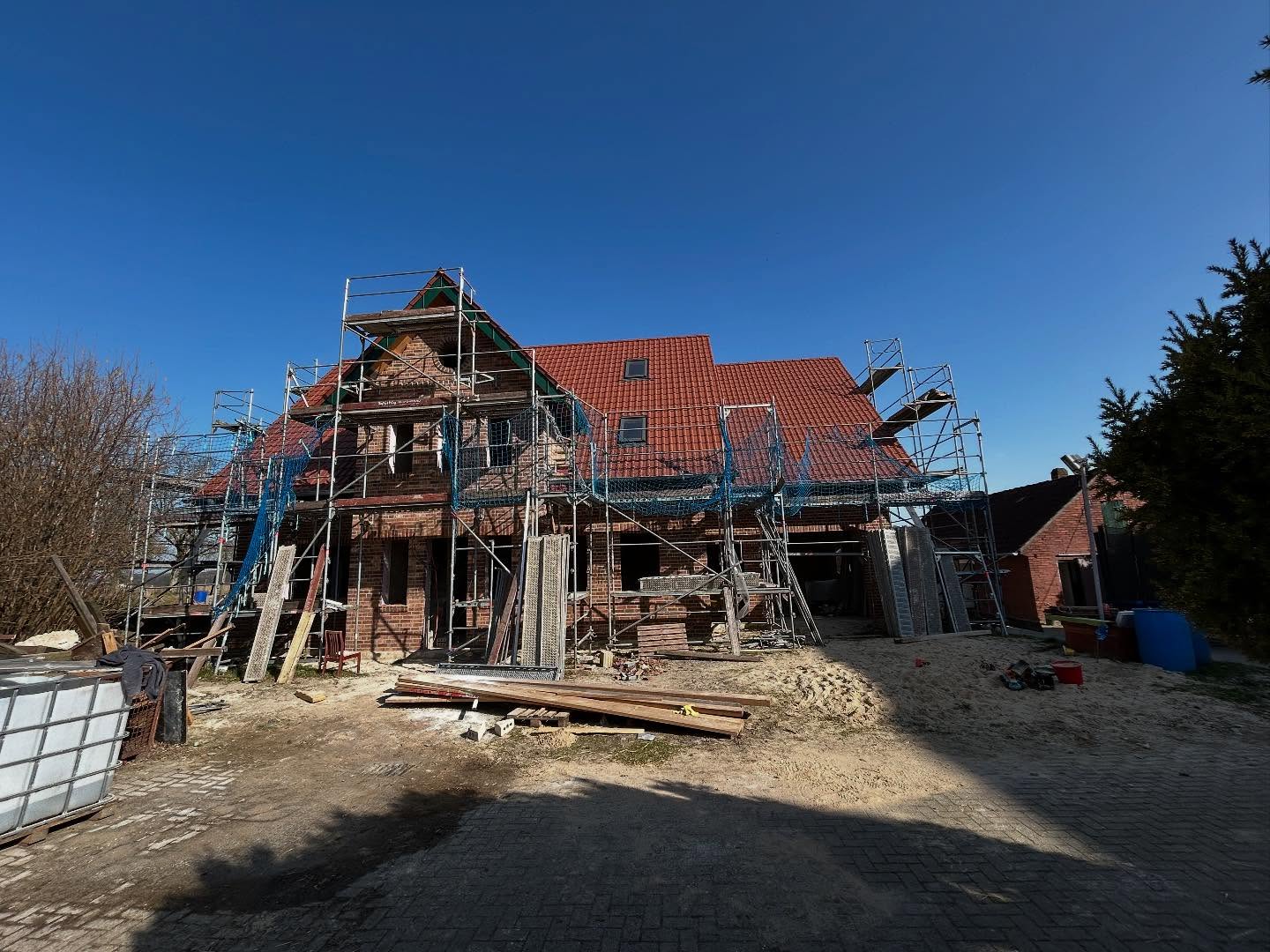 Wohnhaus mit rotem Ziegeldach und Baugerüst auf dem Grundstück