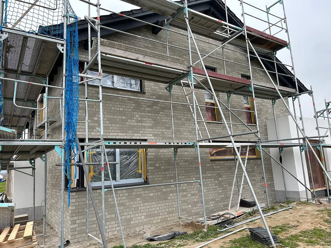 Graue Klinkerfassade mit Gerüst und Fensteröffnungen