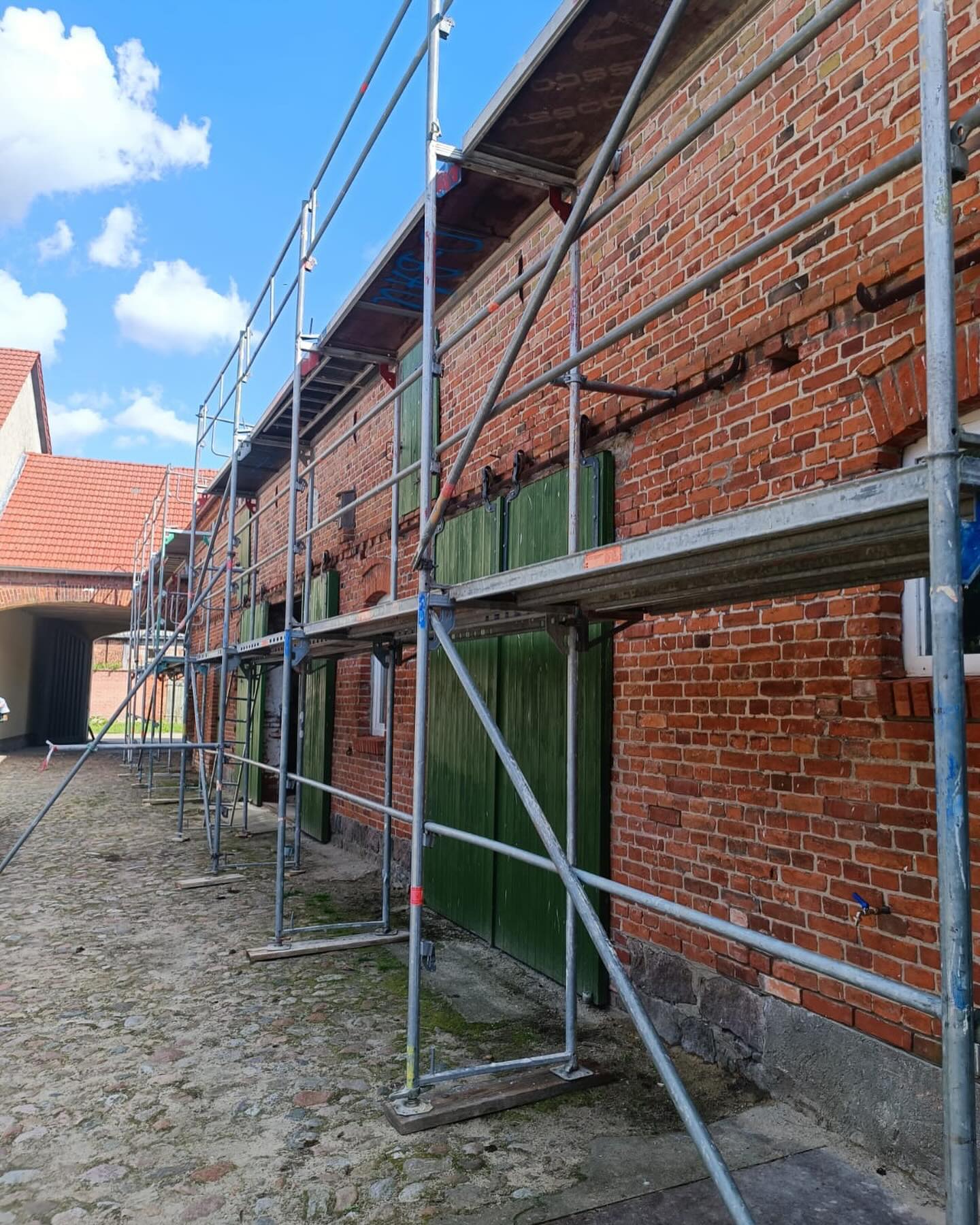 Altes Ziegelgebäude mit grünem Tor und Baugerüst