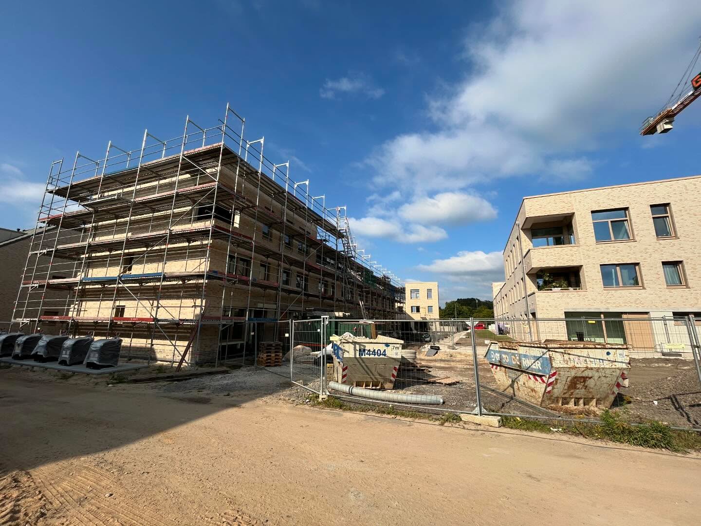 Gebäude in Sandklinker mit Gerüst auf einer Großbaustelle mit Kran
