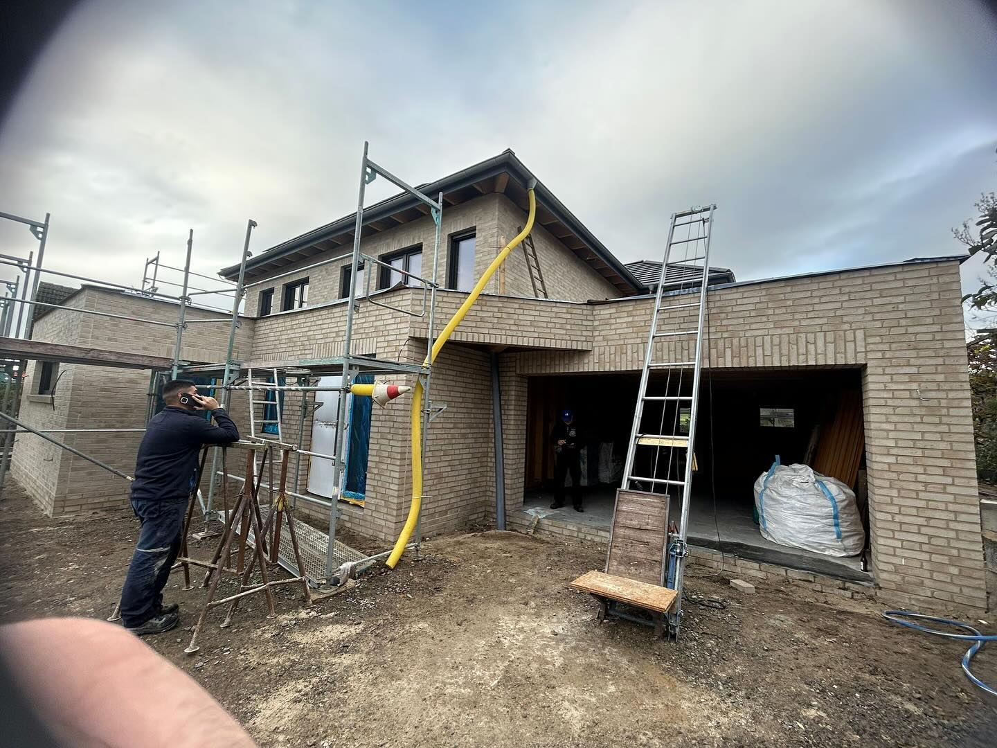 Handwerker bei der Arbeit an einer Sandklinkerfassade mit Garage