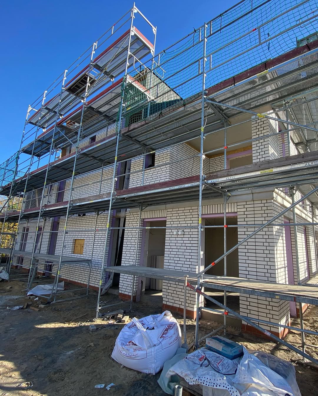 Helle Klinkerfassade eines Neubaus hinter einem Gerüst