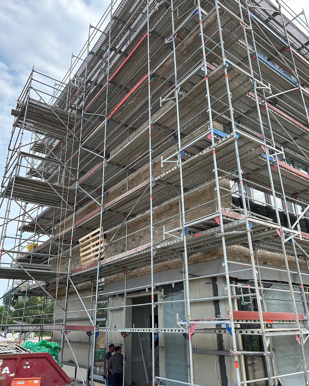 Mehrgeschossiges Gebäude mit Klinkermauerwerk hinter einem Baugerüst