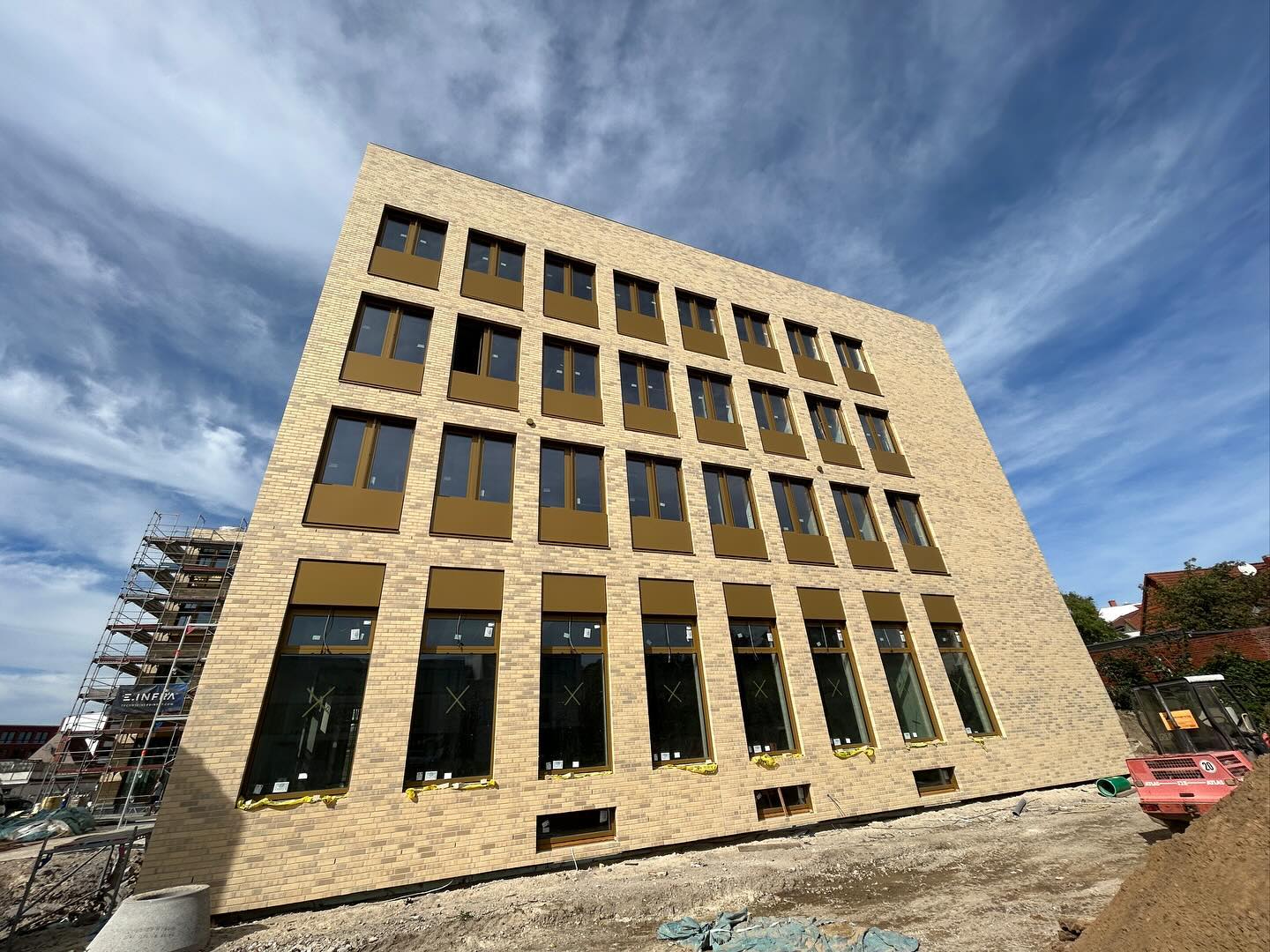 Mehrgeschossiges Gebäude mit beigem Klinker und vielen Fensteröffnungen