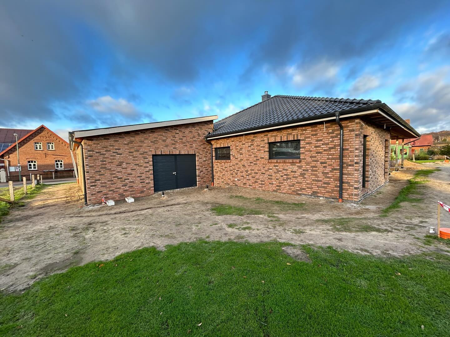Fertig gestelltes Wohnhaus aus rotem Klinker mit Garage und Rasenfläche
