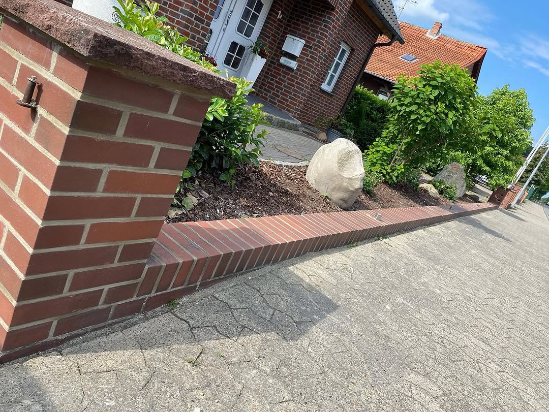 Rote Ziegelmauer neben einer gepflasterten Einfahrt