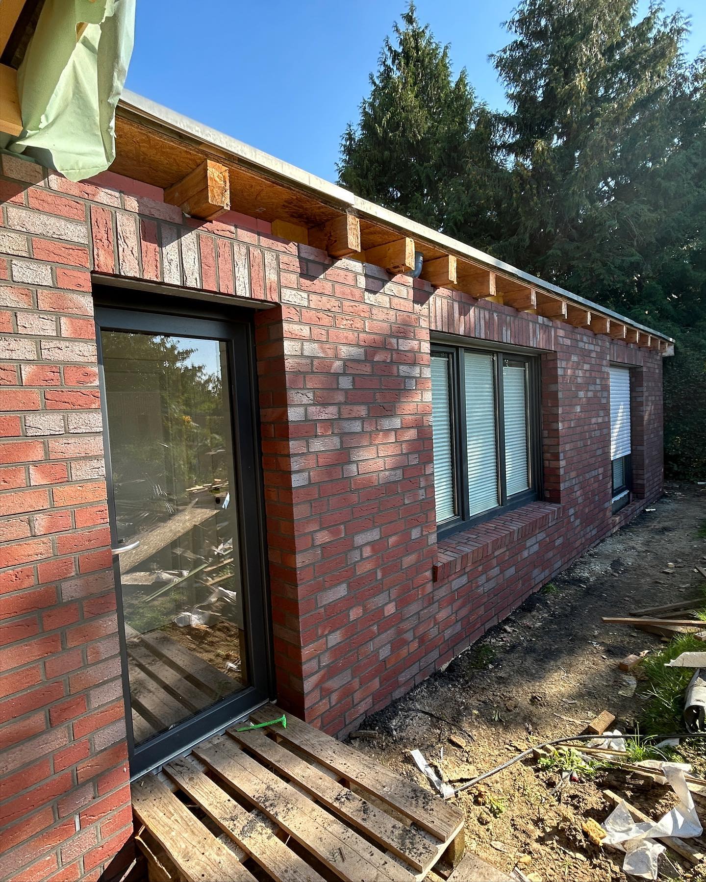 Rotes Ziegelmauerwerk rund um eine Glastür und Fenster