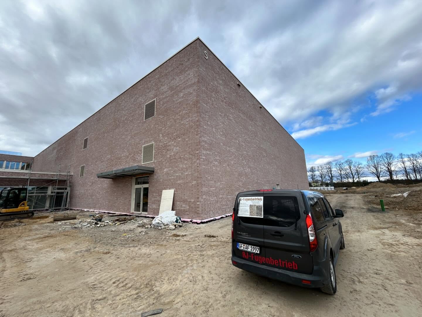Firmenfahrzeug von JF Fugenbetrieb vor einem Klinkerbau auf der Baustelle