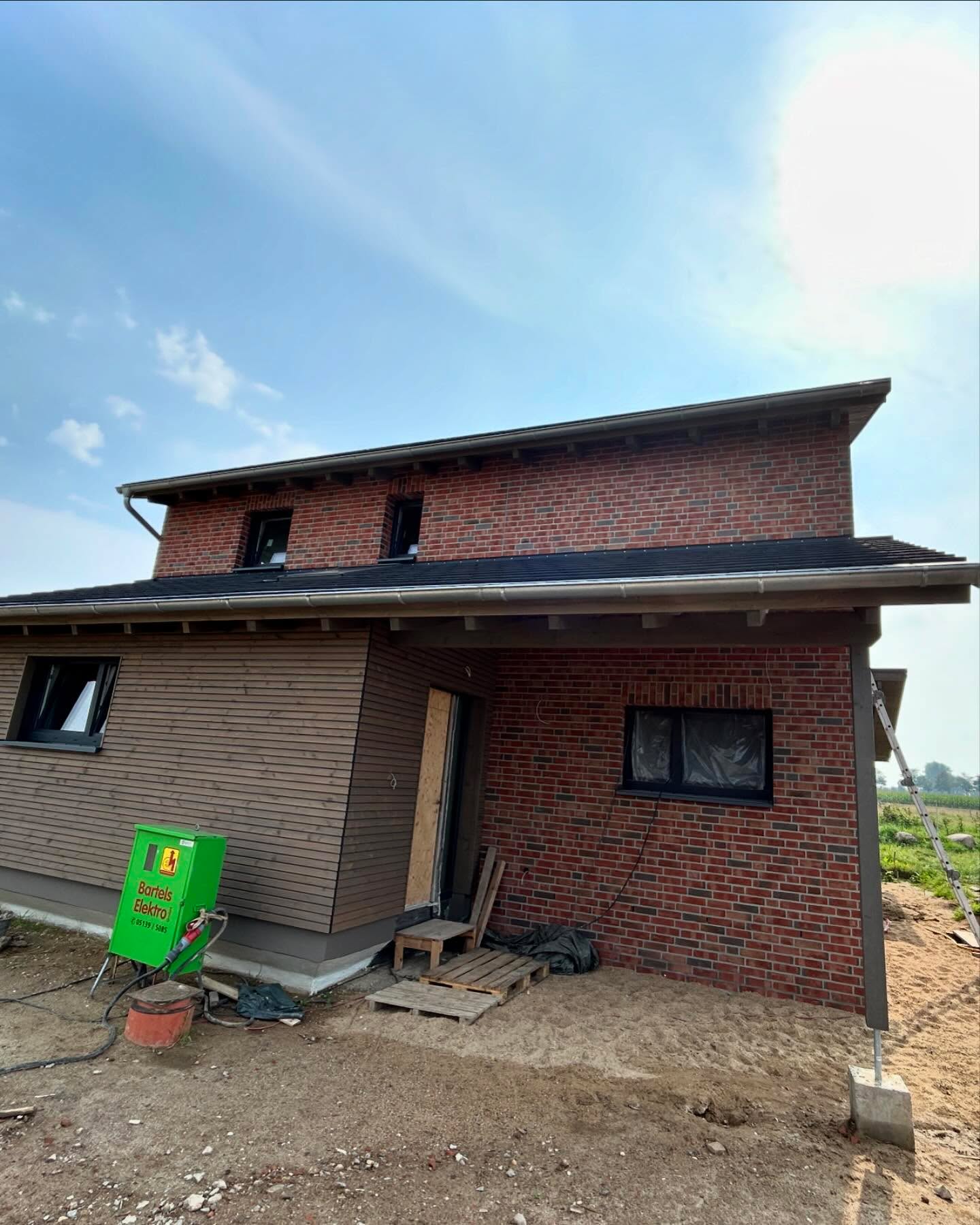 Dunkles Klinkerhaus mit grauem Dach und Vordach am Eingang