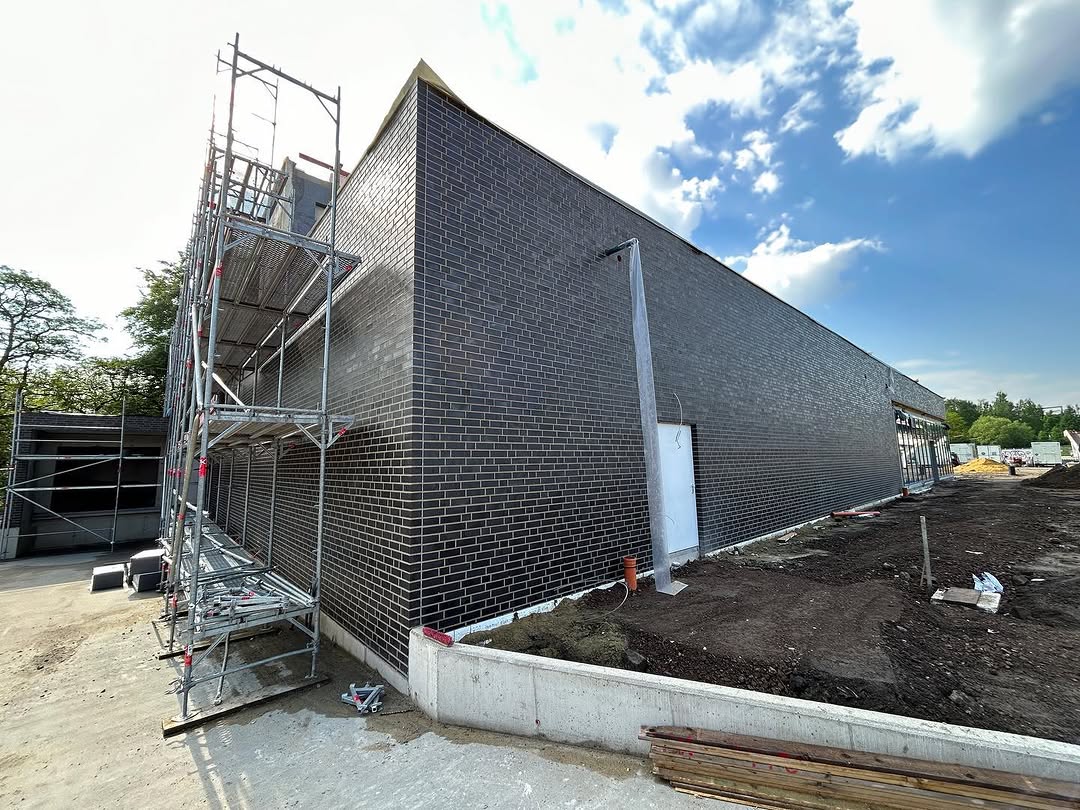 Dunkle Klinkerfassade mit Gerüst und Betonanschluss