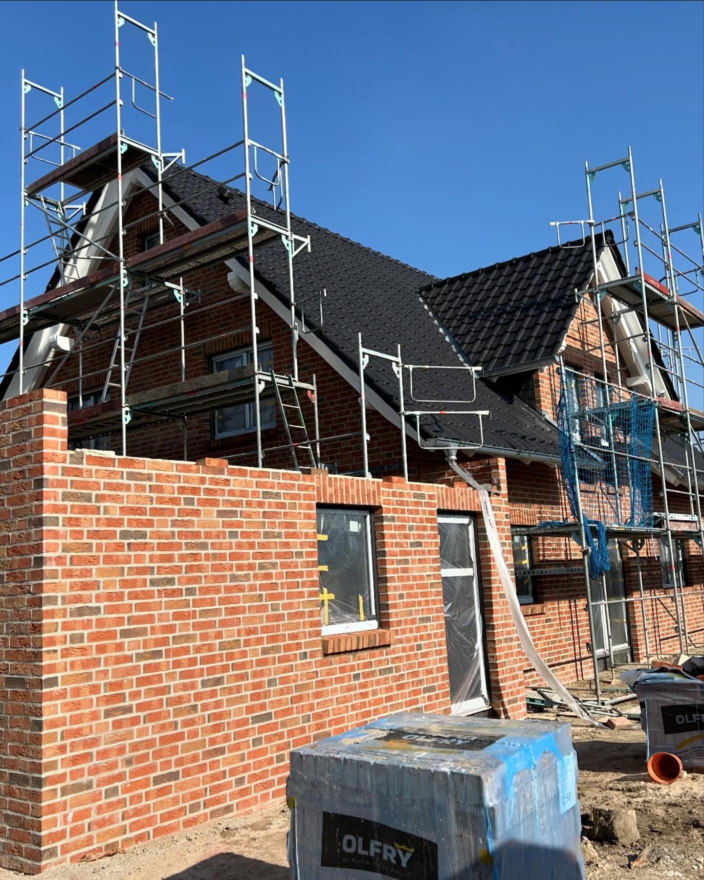 Klinkerhaus mit Gerüst und Dacharbeiten im Giebelbereich