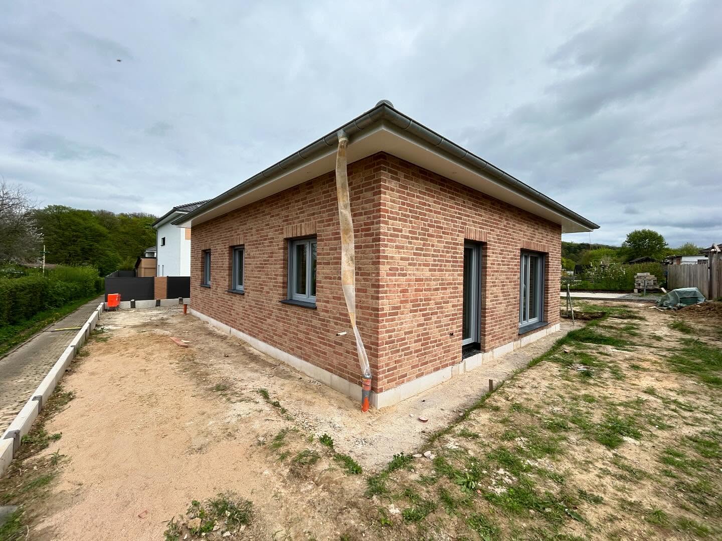 Bungalow mit rotem Klinker und weißer Brüstung auf dem Grundstück