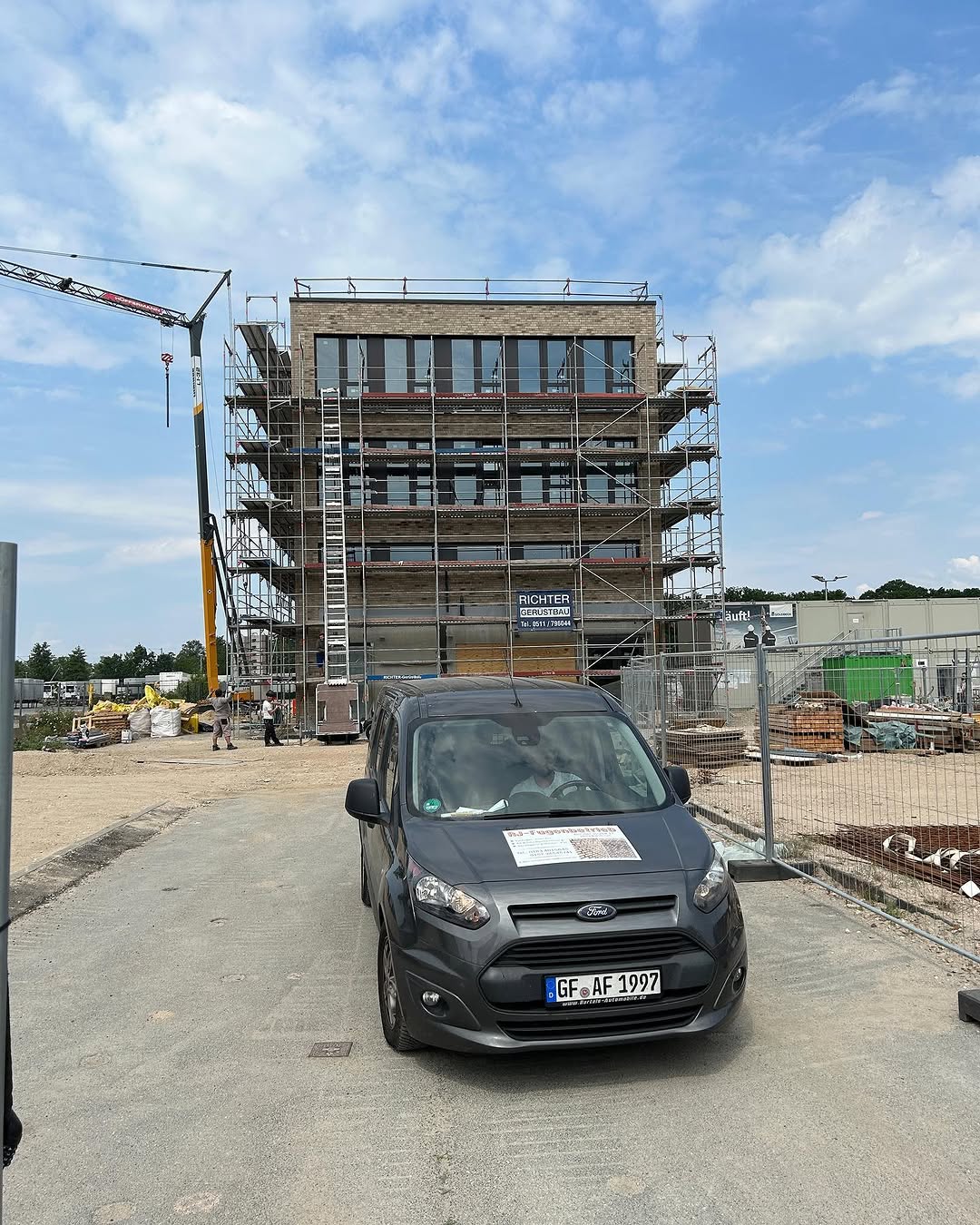 Fahrzeug von JF Fugenbetrieb vor einer Baustelle mit Gerüst