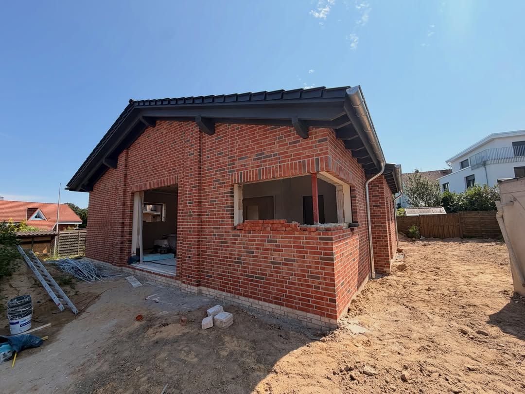 Roter Klinkerbungalow mit offenem Carport im Rohbau