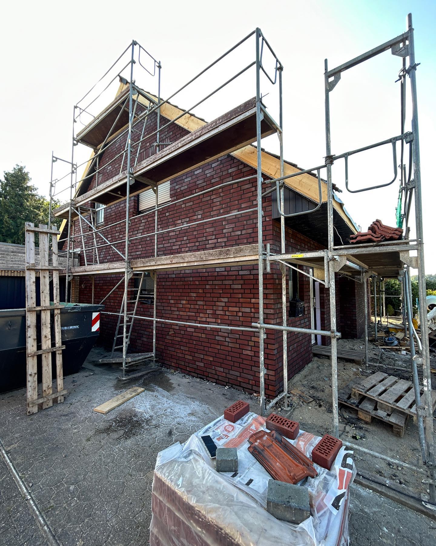 Rote Ziegelfassade eines Hauses hinter einem Baugerüst