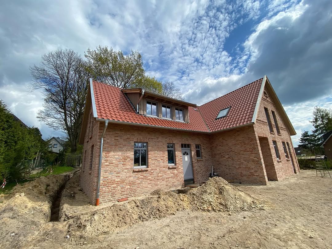 Ziegelhaus mit rotem Dach und Erdarbeiten im Außenbereich