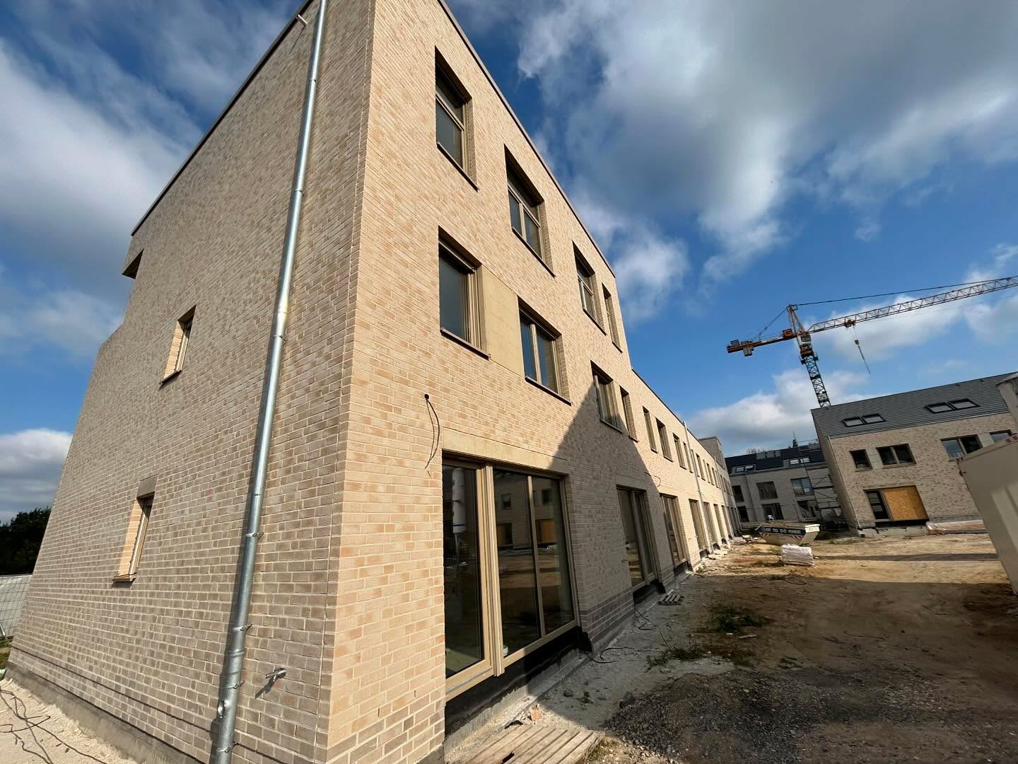 Eckgebäude aus hellem Sandklinker mit Baukran im Hintergrund